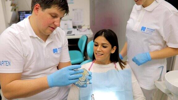 一名牙医在牙科设备上向一名女病人展示牙齿问题