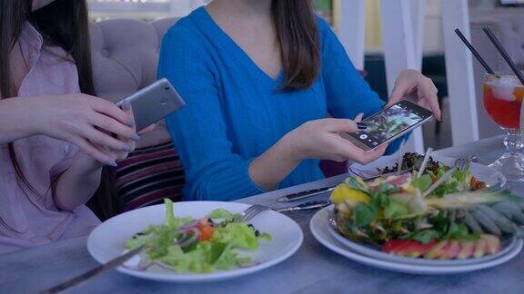 女性朋友的手用手机为美丽的沙拉照片在健康晚餐期间节食减肥在餐厅