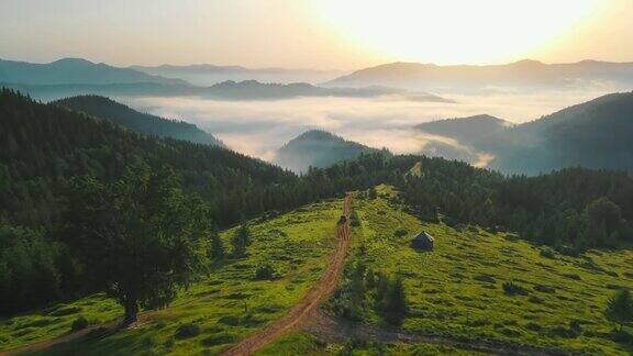 清晨的山景飞行在一条土路和美丽的雾在日出躺在山谷