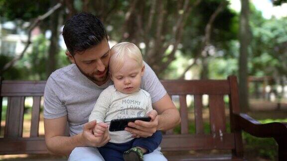 父子俩在公园长椅上玩手机