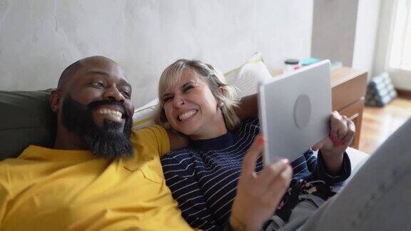 幸福的夫妇一起在家里的床上使用电子平板电脑