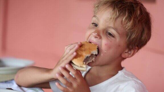 可爱的小男孩在吃汉堡包金发男孩吃了一口汉堡
