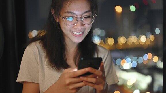 亚洲Gen-z大学开朗的学生戴着眼镜用手机购物晚上在卧室里进行电子商务