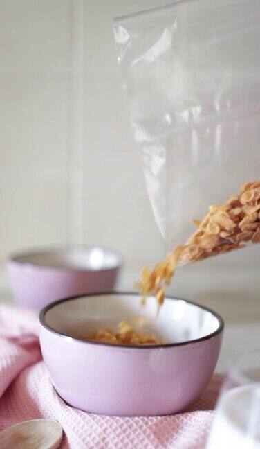 将牛奶倒在白色碗里的全谷物玉米片上慢动作