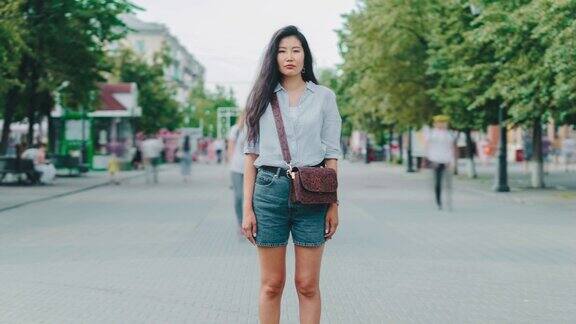 放大严肃的亚洲女孩穿着休闲衣服站在户外的城市街道