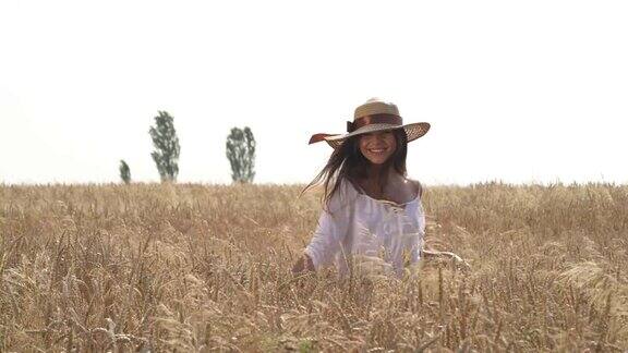一个漂亮的女人戴着草帽在白天走在田野里快乐的女孩享受她的时间