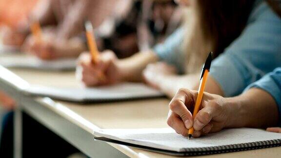 特写的一排学生写在笔记本参加考试手握笔的重点