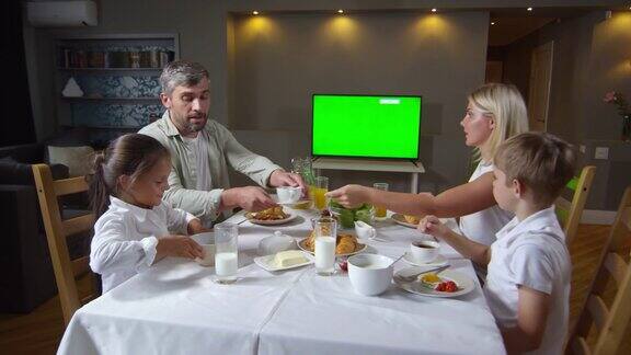 家庭吃早餐和看电视与色度键屏幕