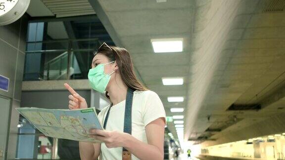 带着口罩的亚洲女性游客在火车站搜索地图