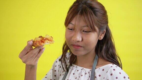 黄色背景下的亚洲青少年正在吃披萨