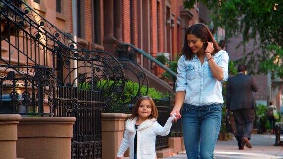 年轻的母亲和女儿走在布鲁克林大街上