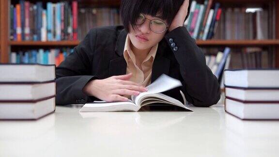 头戴眼镜的亚洲女学生在大学图书馆看书