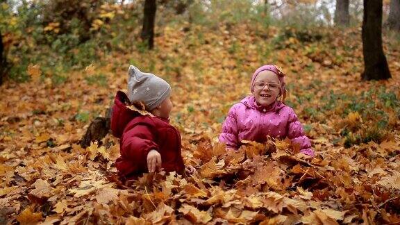 两个快乐的孩子在秋天把落叶抛起来