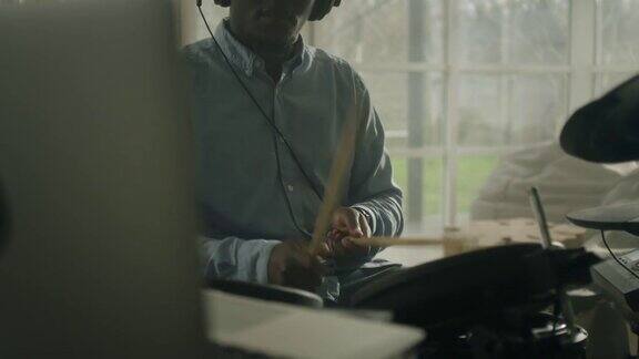 一个非洲裔男子在客厅里练习电子鼓在笔记本电脑上查看游戏教程