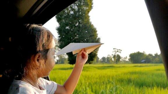 小女孩在车里玩着玩具纸飞机