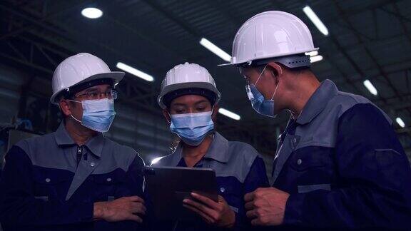 在新冠肺炎疫情下亚洲工程师团队戴着医用口罩在工厂一起工作