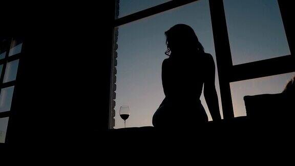 窗台上一个女孩坐在酒杯旁边的剪影