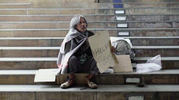 拍摄坐在人行道上无家可归的老人