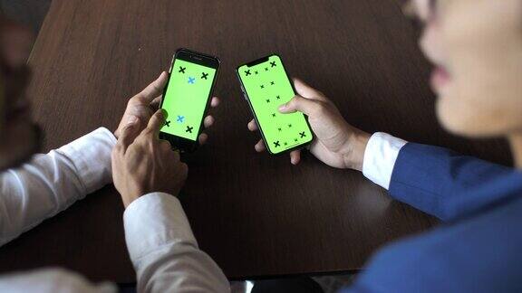 两个人在用绿色屏幕的智能手机