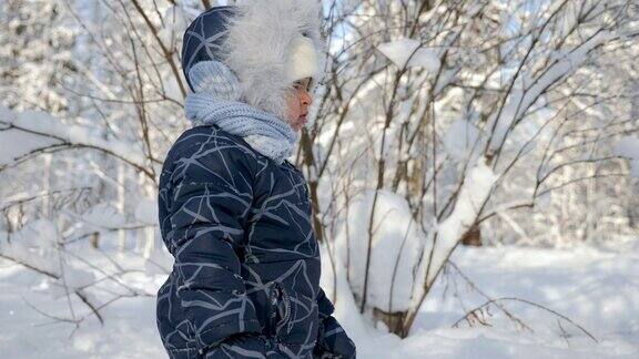 冬天孩子坐在树林里的雪地上