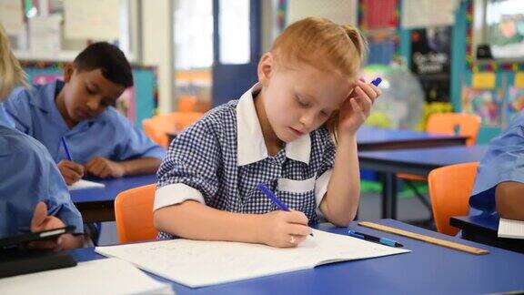 红头发的小学生坐在书桌前写书