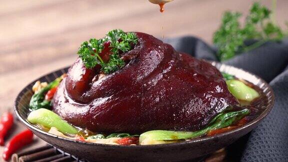 用勺子把可口的酱油倒在盘子里的台湾红烧猪腿上