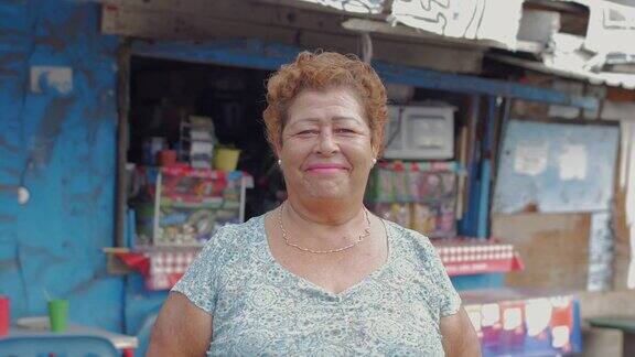 一位上了年纪的西班牙妇女微笑着站在墨西哥的一个小吃摊前