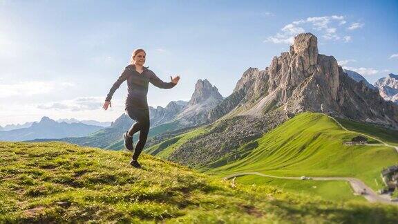 年轻的女运动员在山区的草地上跑步