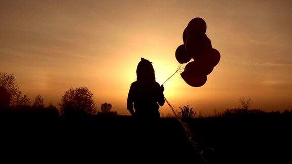 日落时分女孩带着气球在田野里散步