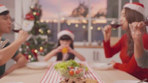 亚洲可爱的家庭成员在家里一起庆祝圣诞派对漂亮迷人的父母在餐桌上碰杯吃着传统的庆祝晚餐
