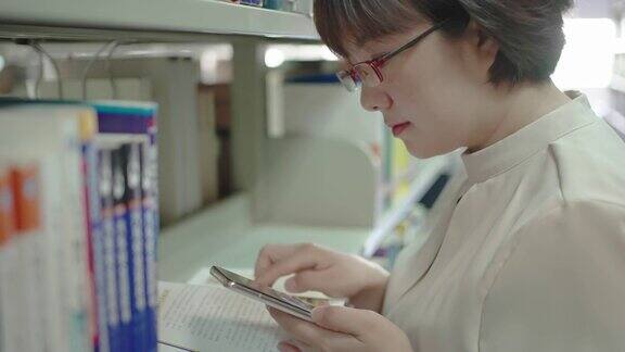 亚洲女人在图书馆用智能手机