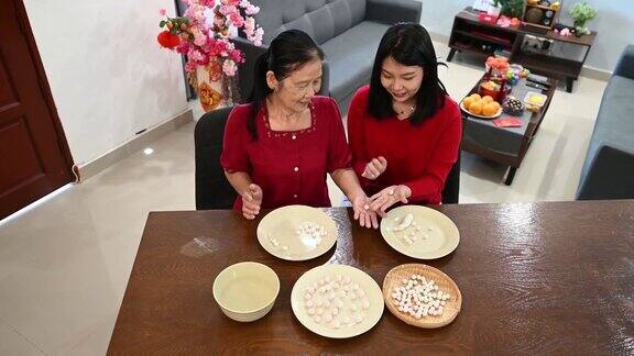 一位亚洲的奶奶和她的孙女正在为庆祝中国新年而准备汤圆