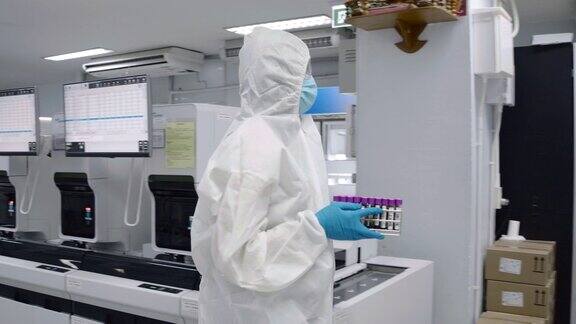 科学家们穿着防护服在无菌室里拿着血液试管在实验室里行走