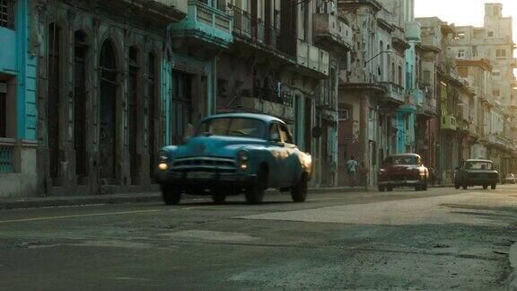 一排五颜六色的老爷车在哈瓦那的老街上行驶