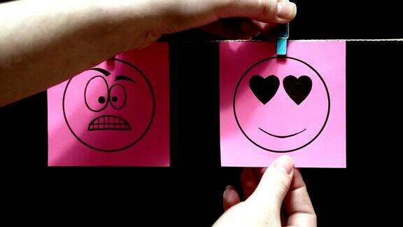 两个贴纸的情绪带着愤怒表情的粉色贴纸粉色的纸上写着爱的表情这些床单是用晾衣夹手工固定在绳子上的黑色背景