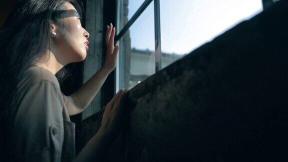 女人透过窗户望着阳光渴望自由