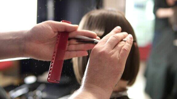 一个理发师的手剪头发的特写镜头理发师在起作用美容沙龙在slowmotion拍摄