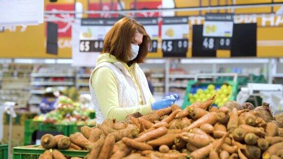 戴口罩的女人在疫情期间在杂货店买胡萝卜