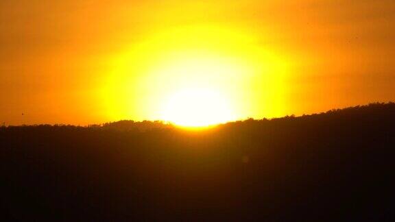 金色的天空和黑暗的山丘背景上的太阳