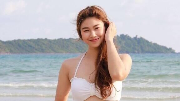 迷人的亚洲年轻女子穿着白色比基尼微笑享受与夏日海滩上的感觉如此幸福和愉悦在泰国热带海滩旅游度假和放松