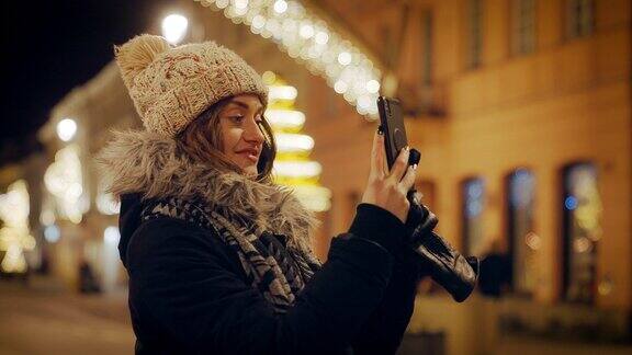 有吸引力的年轻女子一个游客享受节日装饰在一个大城市的圣诞节假期她正在用智能手机自拍转身拍摄照明照片