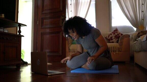 女人在笔记本电脑上看体育课在家做运动