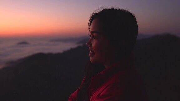 在阳光和雾中一个年轻女子在山上看风景的剪影带着相机独自旅行的背包客假日旅游和度假概念