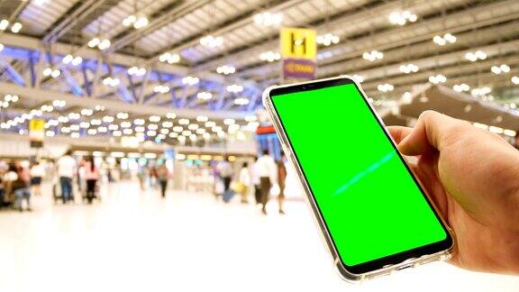 一名男子在机场使用绿色屏幕的手机