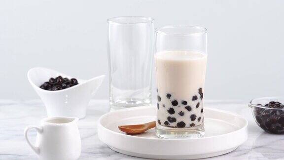 美味的珍珠奶茶在玻璃上台湾流行的饮料在明亮的大理石桌子和白色托盘自制4K放大拍摄视频