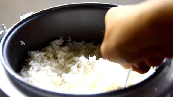 在木桌上用手在锅里煮米饭