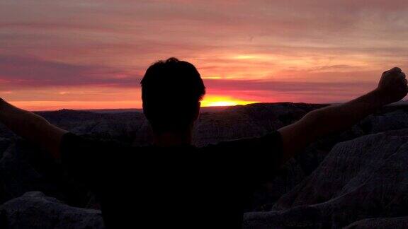 成功的人站在山顶夕阳西下向天举起手臂