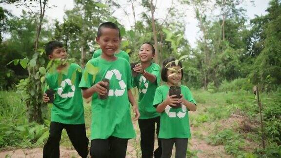 一群环保志愿者儿童男孩女孩在森林里植树世界地球日植树节