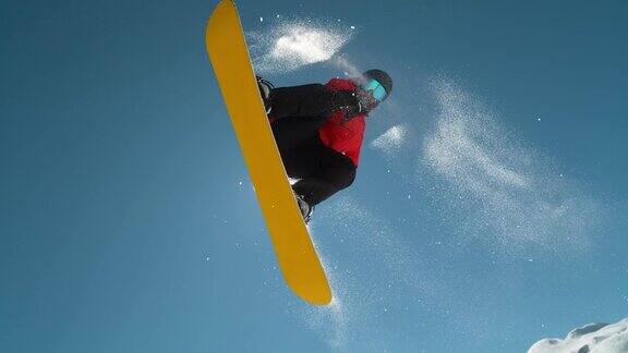 慢动作近景:滑雪板跳跃和飞过太阳在晴朗的蓝色天空