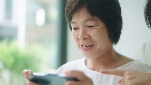 一位年长的女士正在用她的智能手机玩游戏